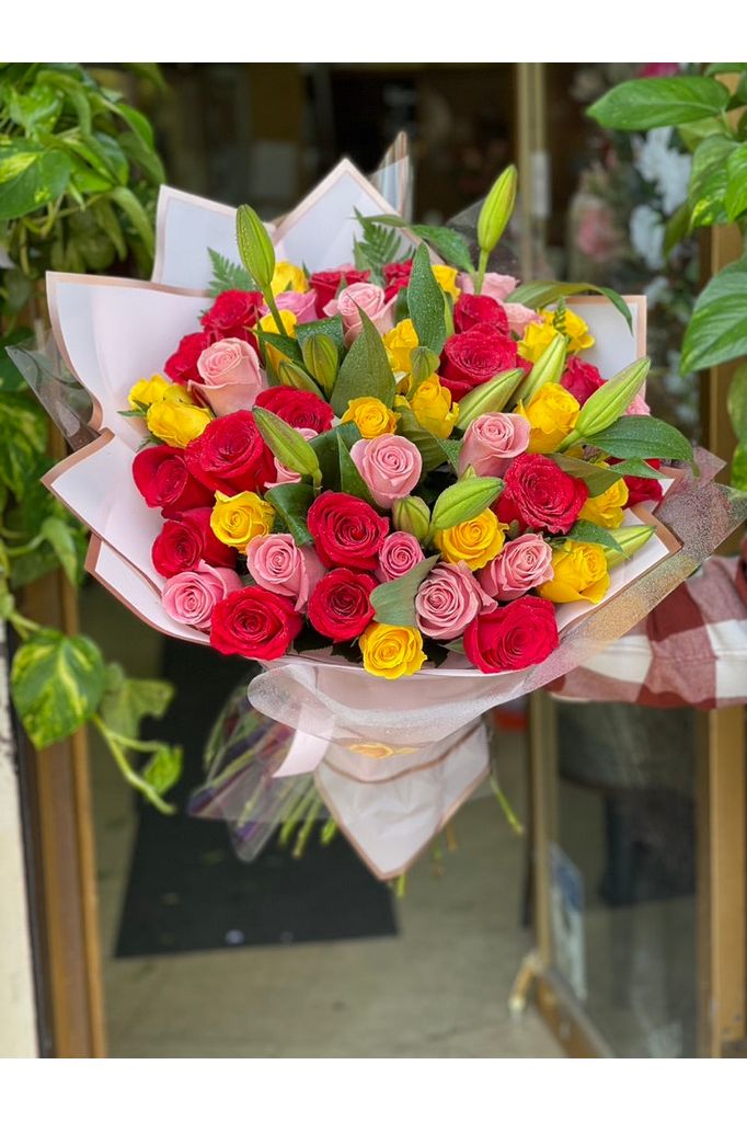 Mixed rose and lily bouquet with red, pink, and yellow roses wrapped elegantly – Eclore Floral NJ