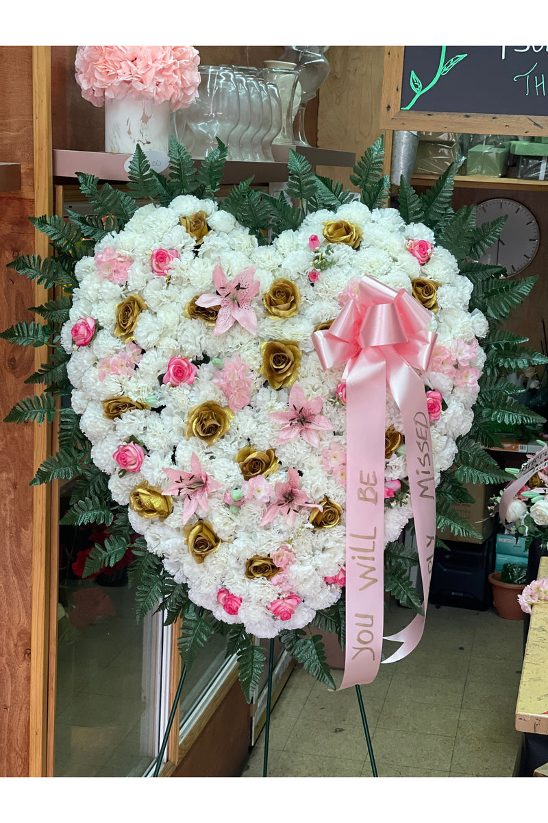 Artificial full heart sympathy arrangement with white carnations, pink roses, lilies, and gold roses on standing easel by Eclore Floral NJ