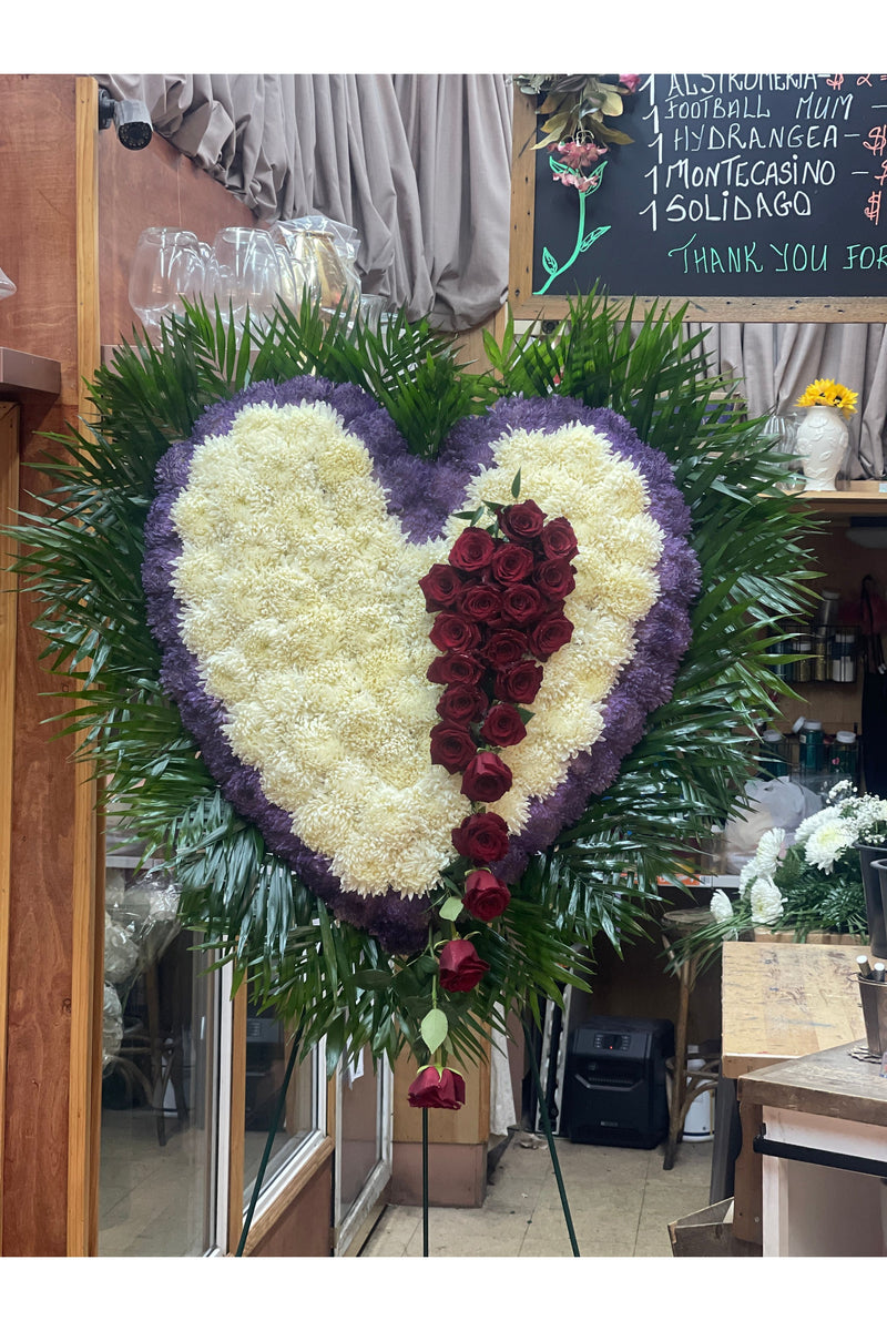 Purple, white, and red bleeding heart funeral standing spray with cascading red roses and purple outline.
