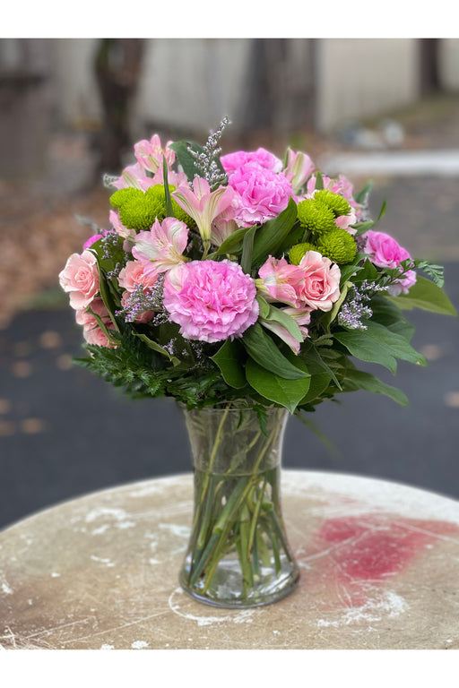 Soft pink flower bouquet with carnations, roses, alstroemeria, and green mums in a glass vase