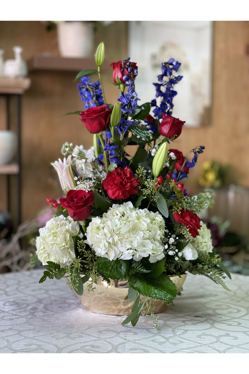 Golden Spray floral arrangement with white hydrangeas, red roses, lilies, and blue delphinium in a designer basket — handcrafted by Eclore Floral Hackensack NJ with same-day delivery