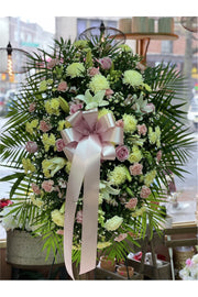 Pink and white funeral standing spray with roses, carnations, chrysanthemums, lilies, and greenery