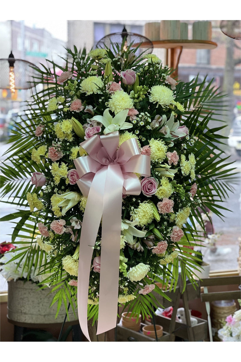 Pink and white funeral standing spray with roses, carnations, chrysanthemums, lilies, and greenery