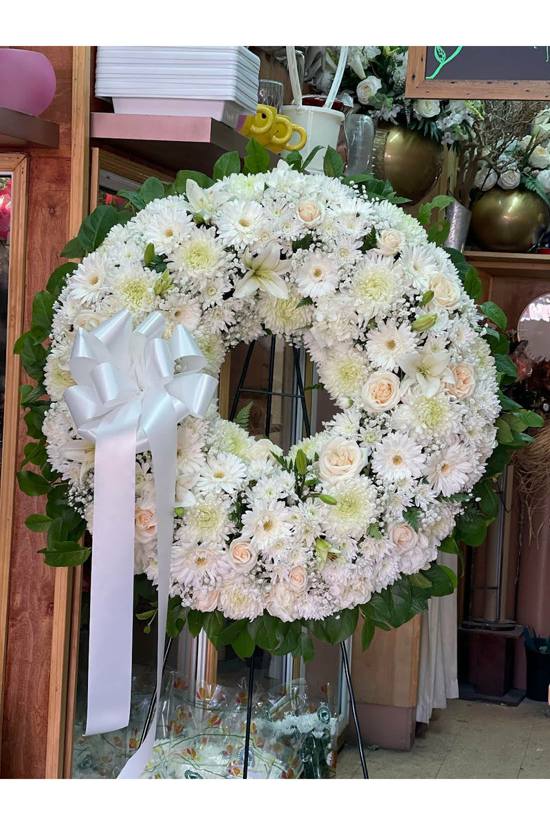 All-white funeral wreath with fresh white flowers, crafted for sympathy by Brooklyn florist.