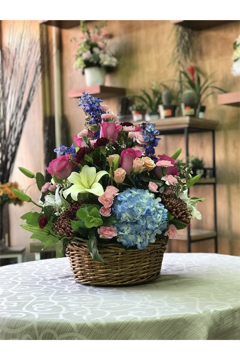 Large mixed flower basket with blue hydrangeas, lilies, pink roses, and delphinium – NJ floral delivery.
