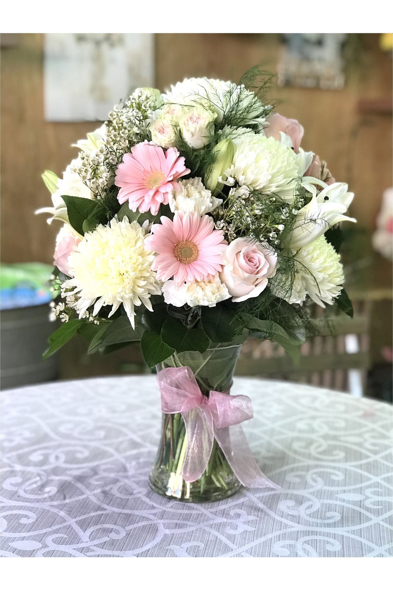 Pink and White Blossom flower arrangement with soft pink gerberas, white mums, lilies, and pastel roses in a clear vase with a pink ribbon — handcrafted by Eclore Floral.