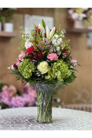 Green hydrangea and berry-accented flower arrangement with roses, lilies, and carnations in a tall vase – New Jersey florist.