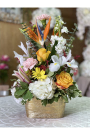 Birds Eye tropical mixed flower arrangement with Birds of Paradise, yellow roses, pink carnations, white hydrangeas, lilies, and daisies in a gold vase