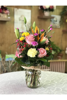 Summer Blossom arrangement with roses, carnations, Bird of Paradise, chrysanthemums, and berries in a glass vase.
