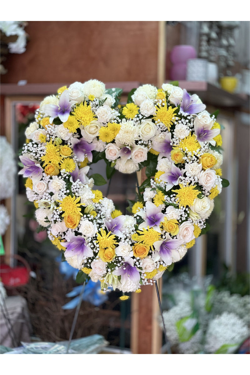 Yellow and lavender open heart funeral wreath with roses, lilies, chrysanthemums, and carnations by Eclore Floral in New Jersey.